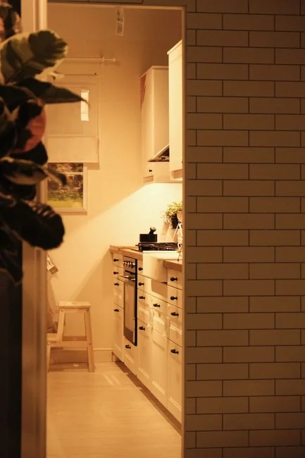 Canapé recouvert d’un drap et lampadaire, avec des cartons emballés dans une pièce claire et spacieuse d’une maison contemporaine neuve
